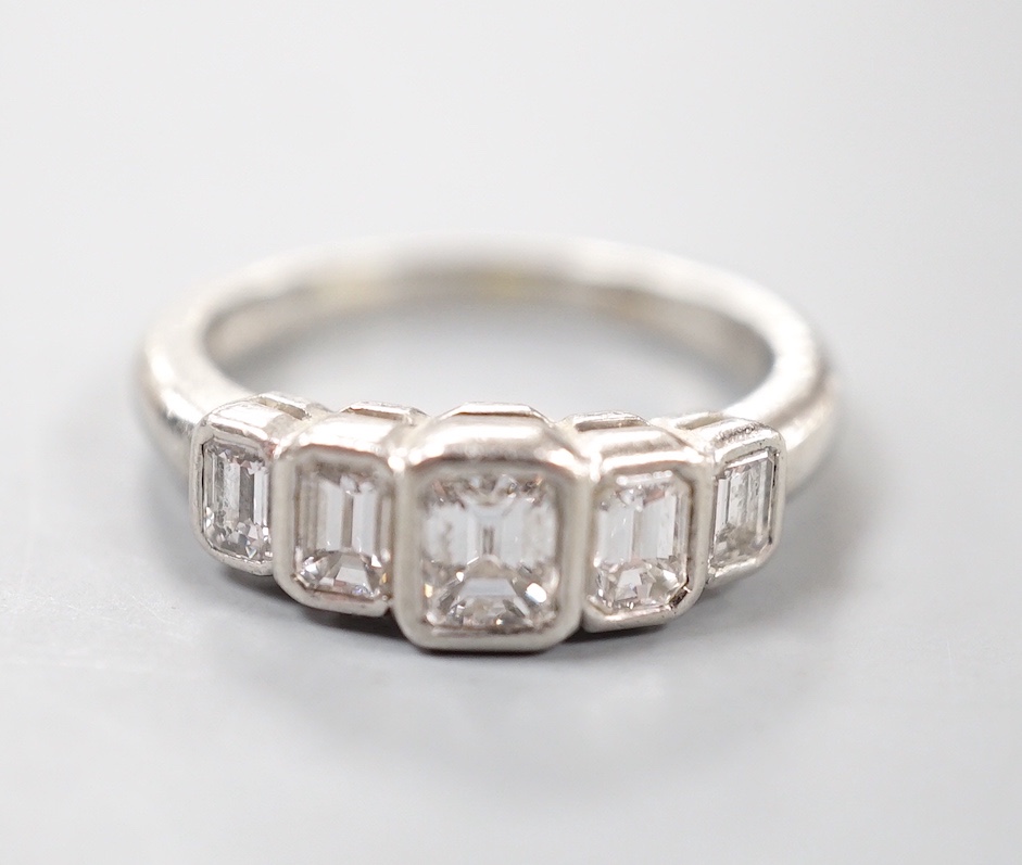 A modern platinum and graduated emerald cut five stone diamond set half hoop ring, size L, gross weight 6.4 grams.